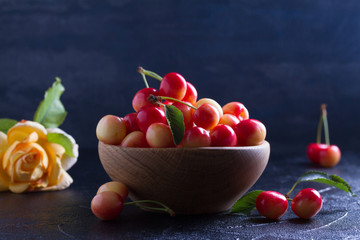 Fresh cherries in wooden bowl on black background. Fresh ripe sweet cherries