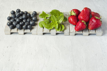 Fresh berries strawberries blueberries mint on a wooden stand, grey background with Copy space for...
