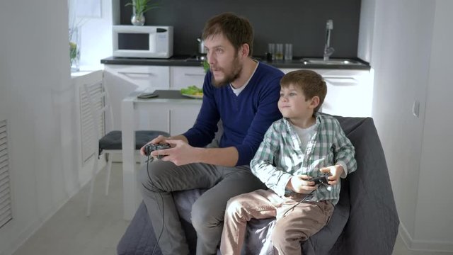 gamers family entertainment, papa with son with game controller into hands play in bright room at vacation