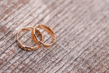 Two golden wedding rings on wood background