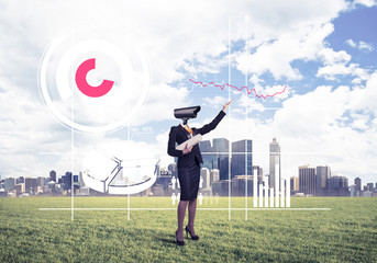 Camera headed woman standing on green grass against modern citys