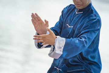 Young man practicing traditional Tai Chi Chuan, Tai Ji and Qi gong in the park for healthy,...