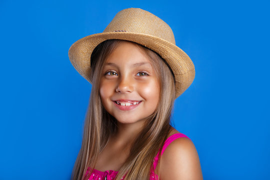 Portrait of young pretty girl in pink dress and hat on blue background .Summer vacation and travel concept