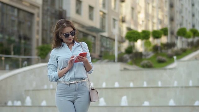 Stylish woman using phone at fountain background