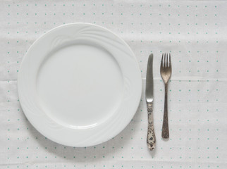 White empty plate with fork and knife on a polka dot tablecloth