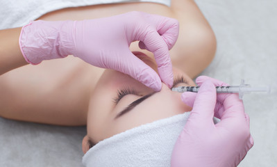 The doctor cosmetologist makes the Rejuvenating facial injections procedure for tightening and smoothing wrinkles on the face skin of a beautiful, young woman in a beauty salon.Cosmetology skin care.