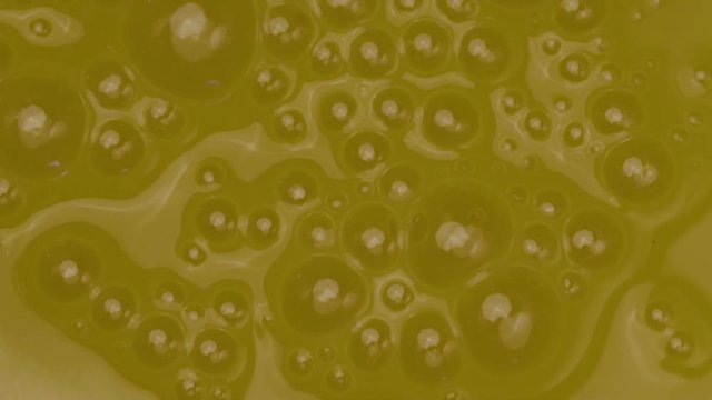 Close-up Of A Yellow Liquid With Bursting Large And Small Bubbles. Conceptual Intro