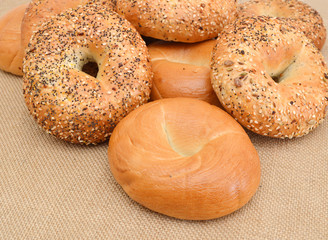 Closeup of a group of assorted bagels on a wood table top with burlap in the background