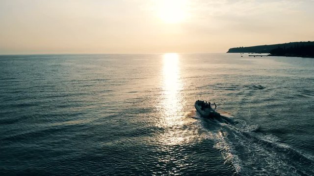 Speedboat is floating across open water at a sunset.