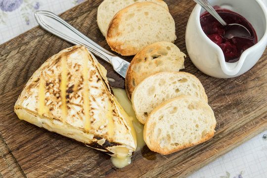 Slice of grilled camembert  with toasted baguettes and cranberry jam