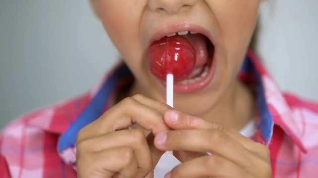Girl trying to bite lollipop, bad effect of sugar on teeth, dental care concept