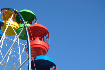 Multicolored Ferris wheel against the blue sky. Close-up.