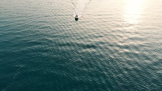Top view of a speedboat floating through the open water. Sea at sunset.