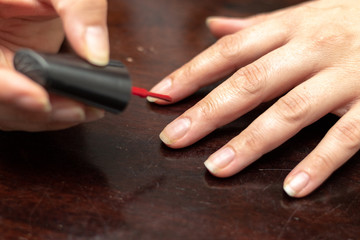 Woman vanishing her finger nails with red enamel