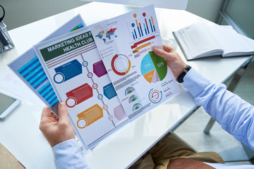 Crop shot from above of man creating new modern project with colorful charts working at desk. 