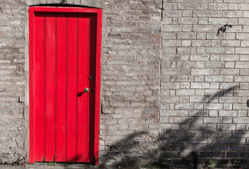 Closed wooden door bright red on a brick wall