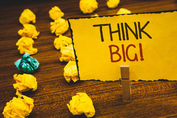 Fototapeta premium Handwriting text Think Big Motivational Call. Concept meaning Have great ideas Dream of something amazingClothespin holding Yellow paper ideas crumpled papers wooden background.