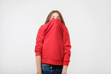 A girl with a social phobia hides her face in a sweater.