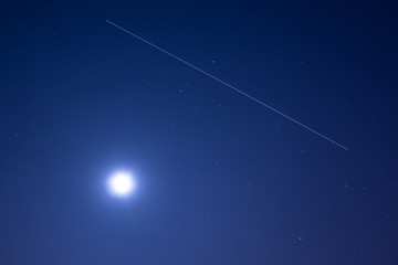 Fototapeta na wymiar International Space Station ISS trail crossing sky with stars and overexposed moon