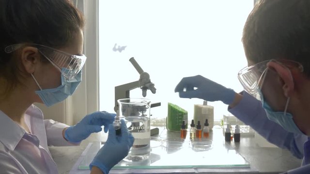 laboratory professional mix fluids in large glass in workplace close-up in vivid lighting indoors