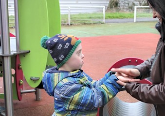 Defect,childcare,medicine and people concept- happy mother and son with down syndrome  playing in a...