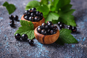 Black currant with leaves in wooden bowls