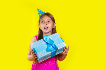 Studio portrait of a little girl wearing a party hat on her birthday. Cute girl open her birthday gift box