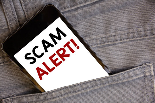 Handwriting text writing Scam Alert Motivational Call. Concept meaning Safety warning to avoid fraud or virus attacksConcept on cell phone into jean pocket white screen black and red letters.