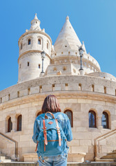 Woman tourist with backpack admires a splendid view of the fisherman bastion, that is one of the...