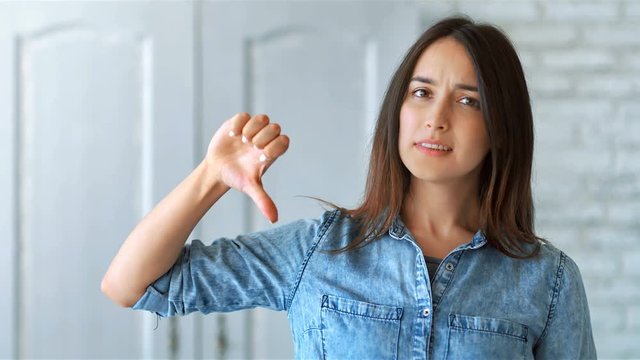 Beautiful young woman showing thumbs down sign to dislike