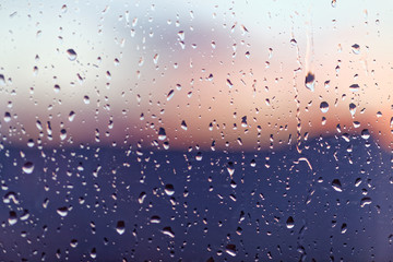 Water rain drops on the window glass on sunset. Shallow depth of field. Cityscape silhouette.