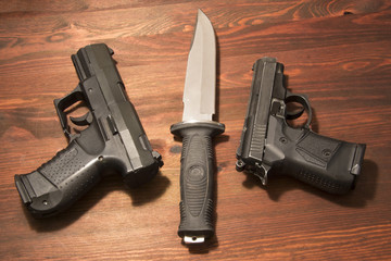 two black pistols and a large military knife on the boards