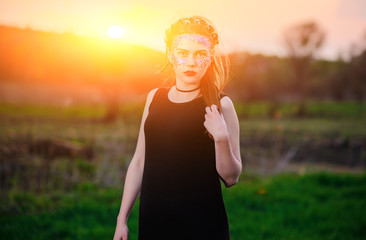 A young beautiful woman with a violet shine on her face standing on the grass and looking at the...