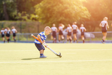 Naklejka premium Small funny boy playing field hockey with stick. Concept field hockey image with copy space