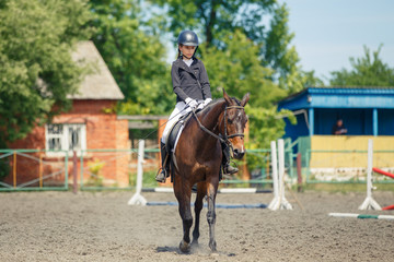 Teenage girl riding bay horse performing dressage test on equestrian competition