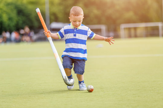 Small funny boy playing field hockey with stick. Concept field hockey image with copy space