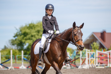 Teenage girl riding bay horse performing dressage test on equestrian competition