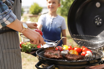 Happy family having barbecue with modern grill outdoors