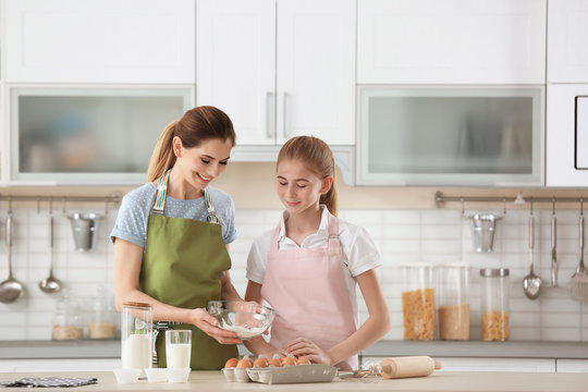 Mother and her daughter making dough at table in kitchen