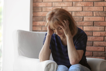 Senior woman suffering from depression in armchair