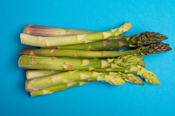 Delicious bunch of raw ripe green asparagus new harvest isolated on trendy blue background flat lay...