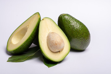 Fresh organic ripe green whole and sliced Fuerte avocado with leaves, copy space close up isolated on white background