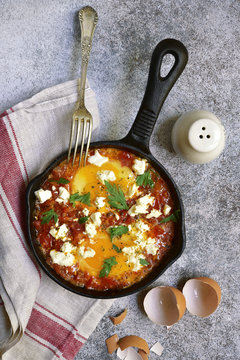 Shakshouka (spicy tomato stew with chicken eggs) with feta cheese - traditional dish of israeli cuisine.Top view.