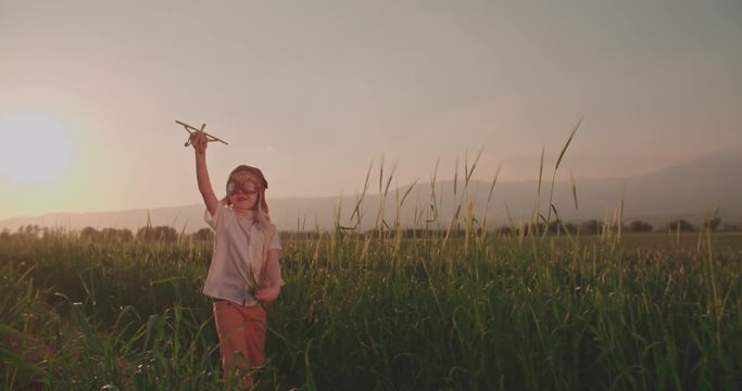 emotional shot happy boy with toy airplane in wheat field is running. dream, childhood, memories concept.Slow motion, sunset time.