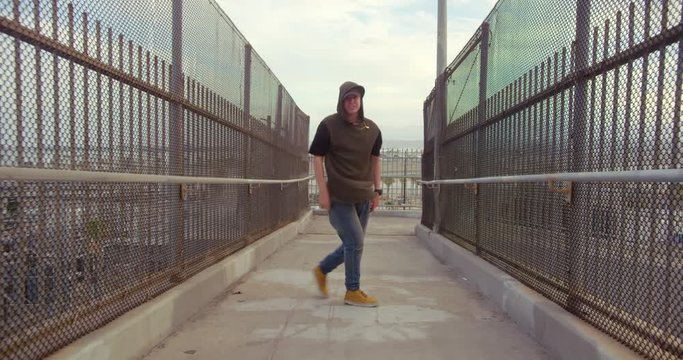 Man hip hop dancing across freeway overpass in city at sunset