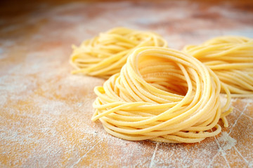 raw homemade spaghetti nest with flour on a wooden table. fresh Italian pasta