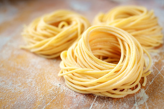 raw homemade spaghetti nest with flour on a wooden table. fresh Italian pasta