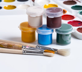 Gouache in jars, brushes and watercolors on a white background