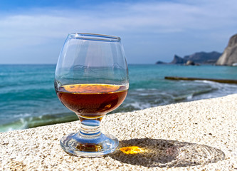 A glass of cognac on the background of the sea.