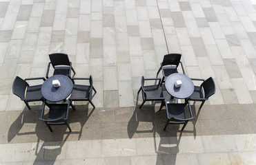 Two unoccupied tables in a street cafe.